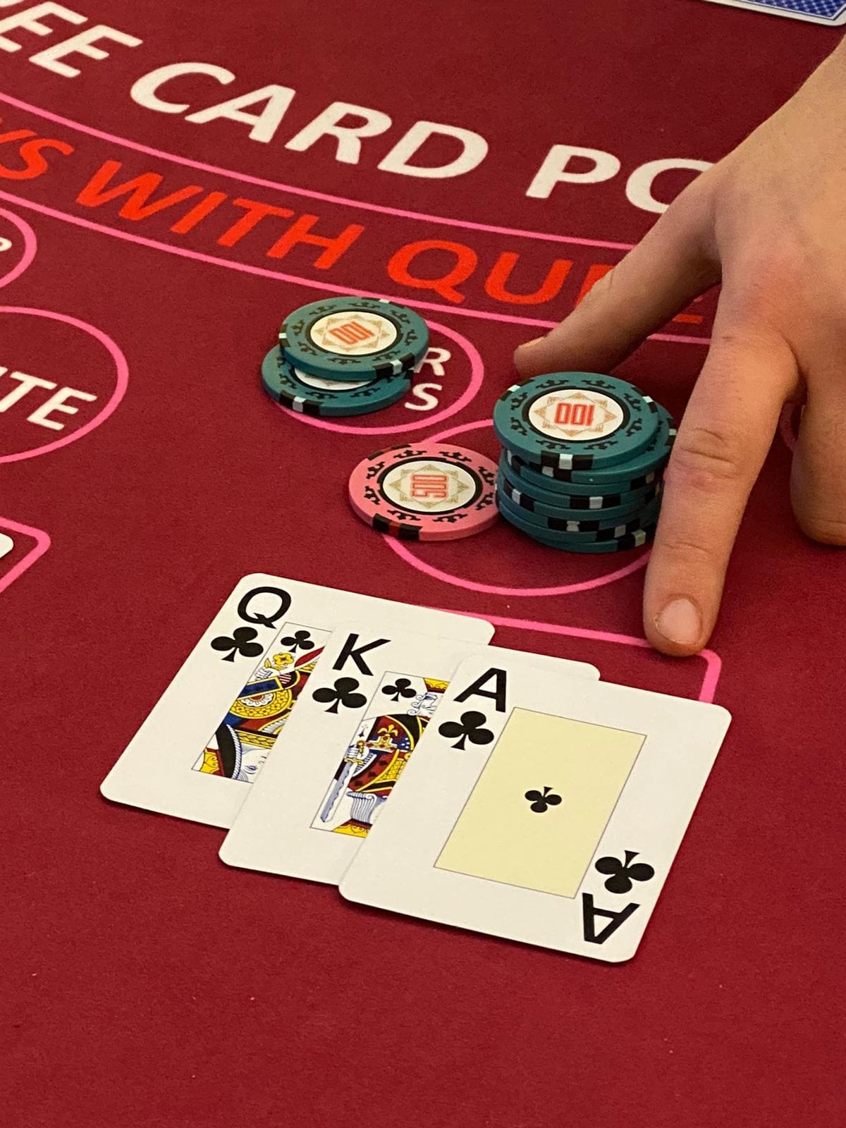 Three card poker hand with chips on red felt table