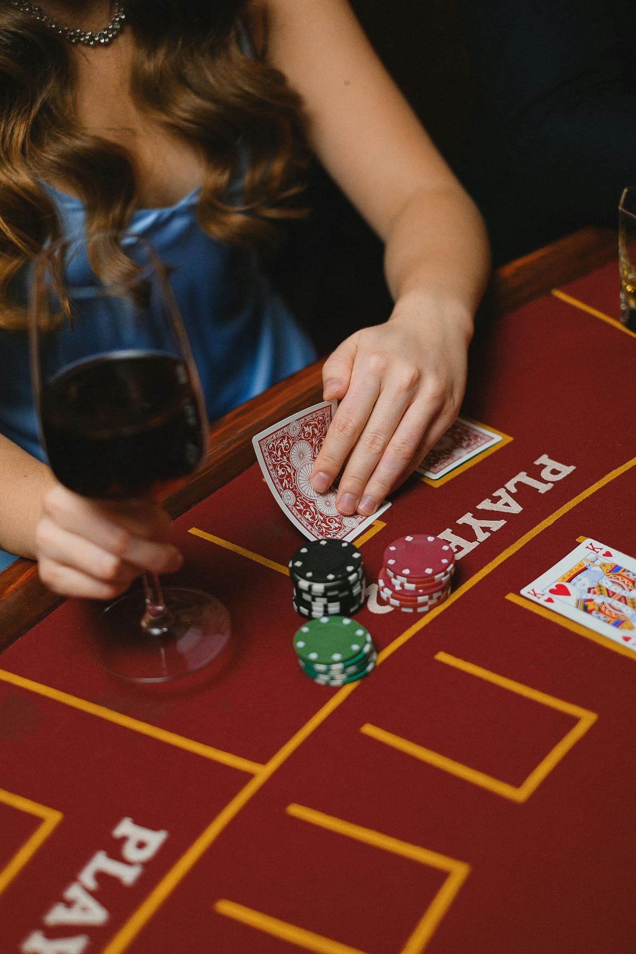 Guest playing cards with wine at casino table